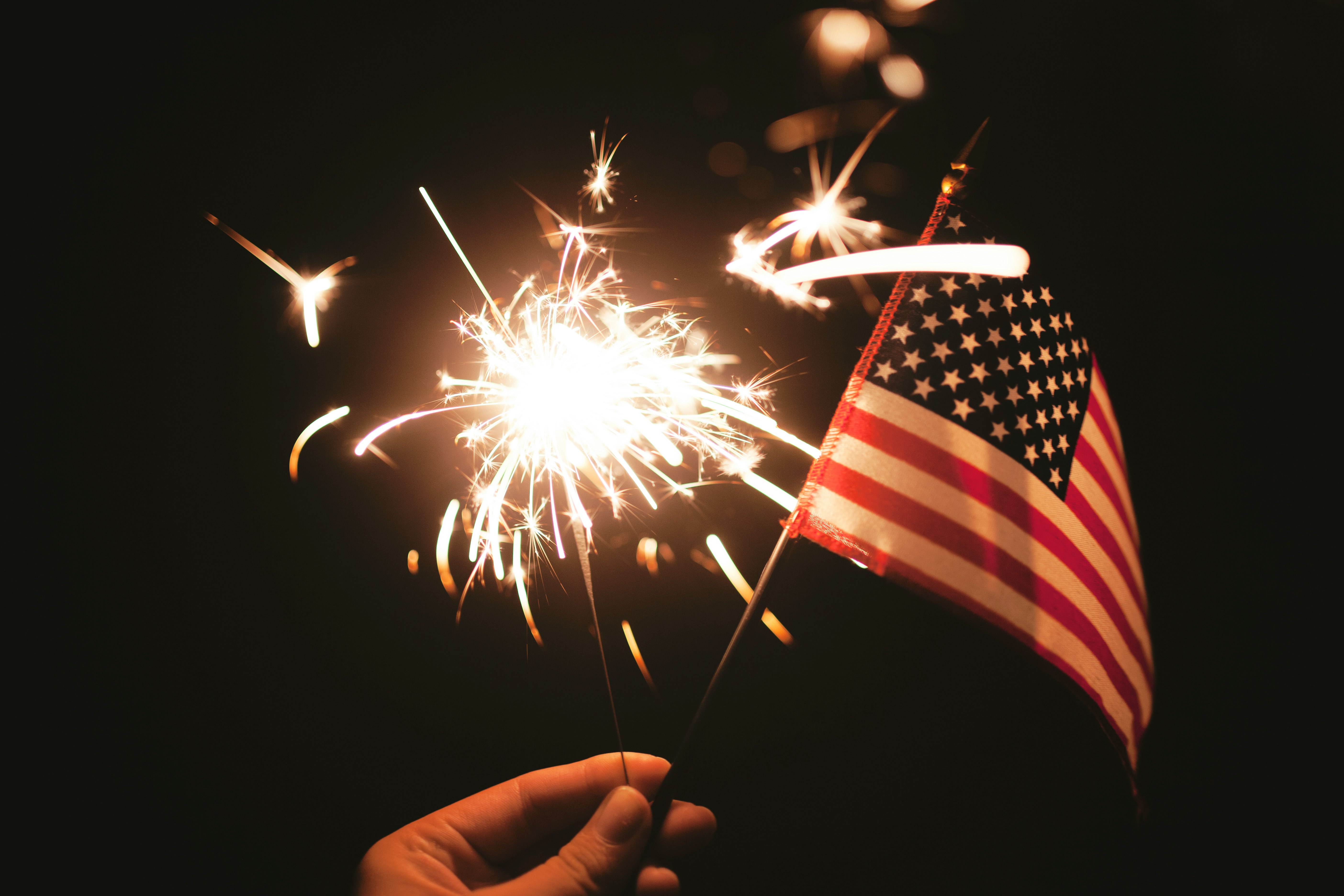 time lapse photography of sparkler and U.S.A flag let